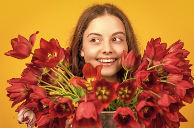 Happy girl hold spring tulip flowers on yellow background