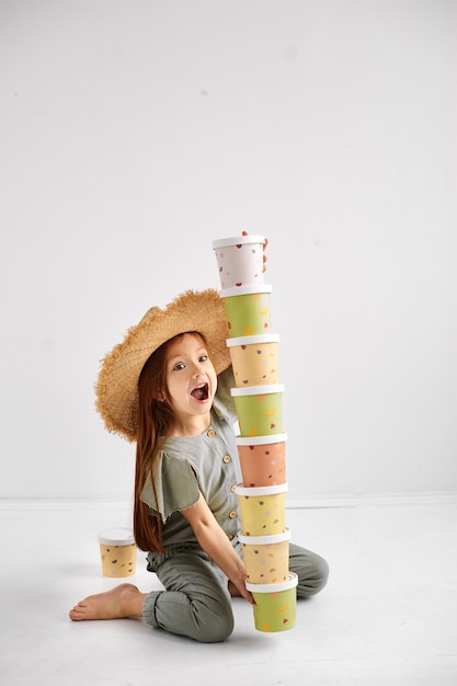 Happy girl hold a tower of colored paper trays. Disposable eco tableware concept.