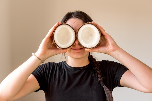 Happy girl holding coconut in front of her eyes