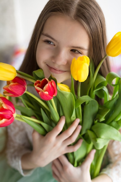 Happy girl holding a large bouquet tulips in his hands