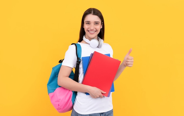 コピーブックと黄色の背景のプライベート教師にノートを保持している幸せな女の子