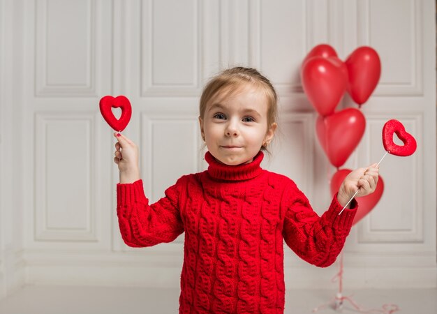 Photo happy girl holding two hearts on a stick on a white background