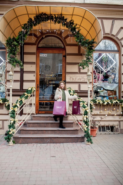 Happy girl holds paperbags with symbol of sale in the stores with sales at Christmas