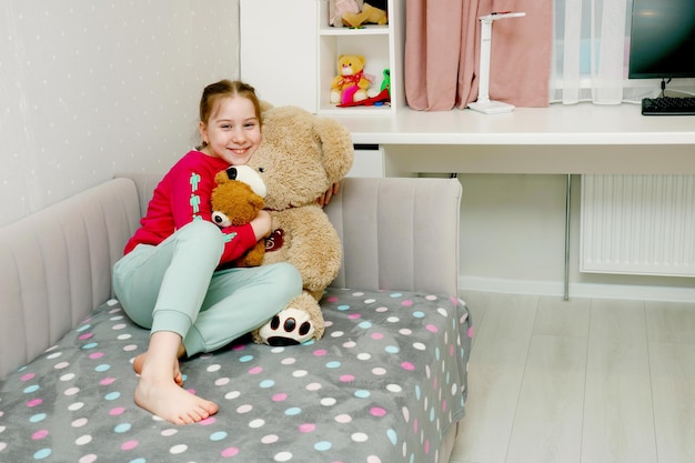 happy girl at home on bed hugging soft teddy bear toys