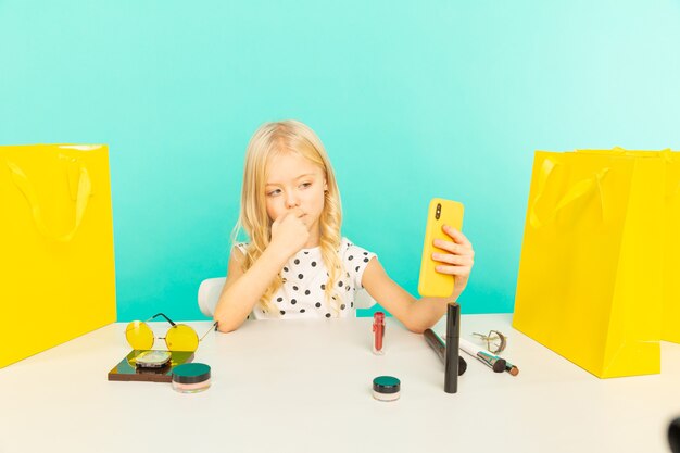 Happy girl at home speaking in front of camera for vlog. Little kid working as blogger, recording video tutorial for Internet.