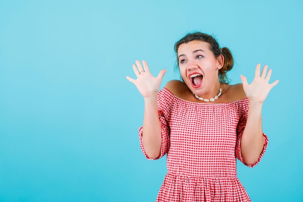 Happy girl is looking up by raising up her handfuls on blue background