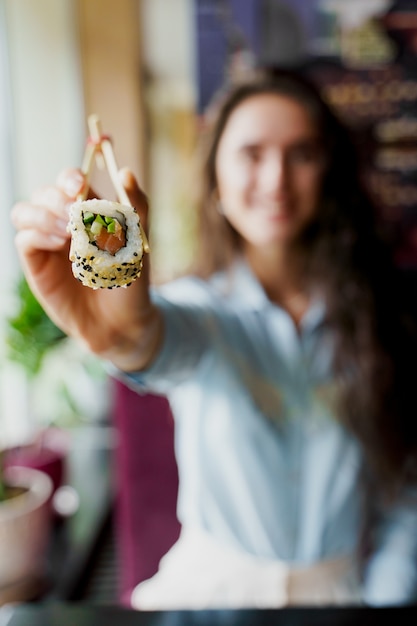 Happy girl is offering sushi in japanese restaurant