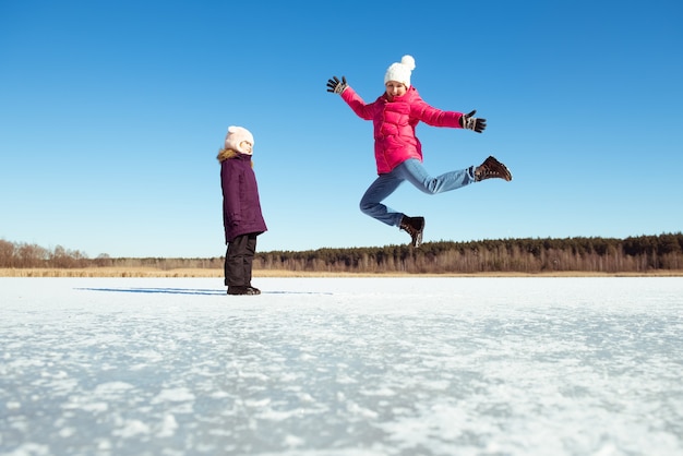 青い空と雪の背景を飛び越えて幸せな女の子