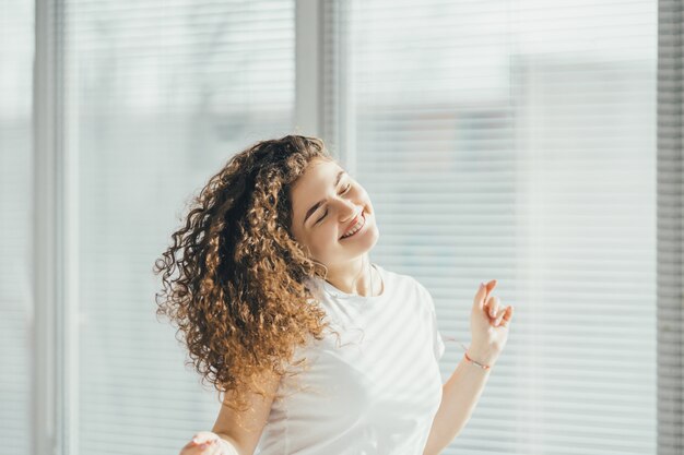 Photo the happy girl listening the music near the window