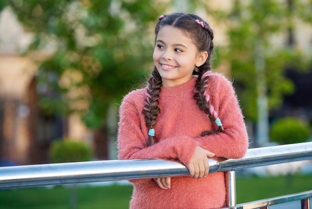 Happy girl looking aside leaning on railing Teenage girl smiling outdoors Teen girl with pigtails