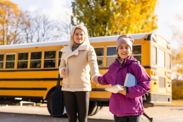 Ragazza felice che guarda la madre con lo scuolabus