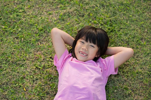 芝生の遊び場に横たわっている幸せな女の子