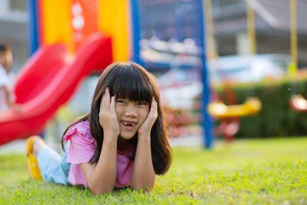 芝生の遊び場に横たわっている幸せな女の子