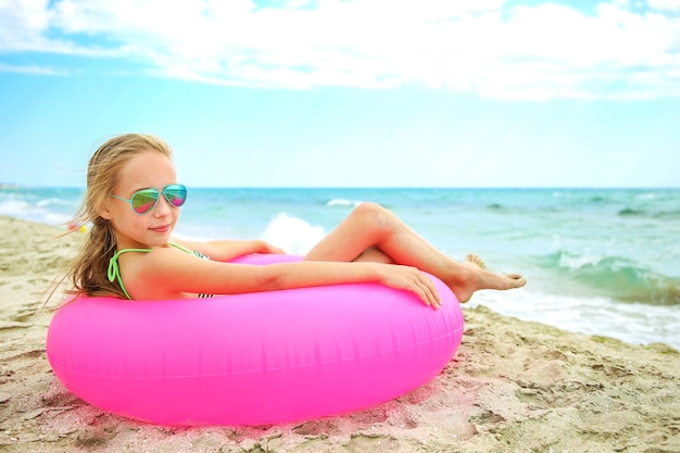 Happy girl lying on pink inflatable circle.