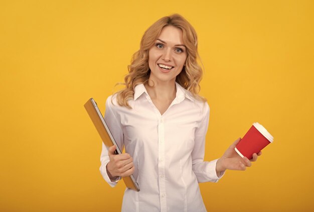 Happy girl manager with laptop hold takeaway drink in paper cup yellow background tea break