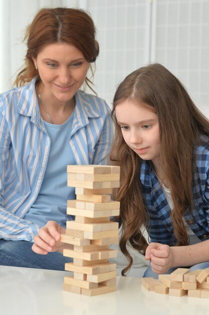 幸せな女の子と母が家でブロックで遊んでいます