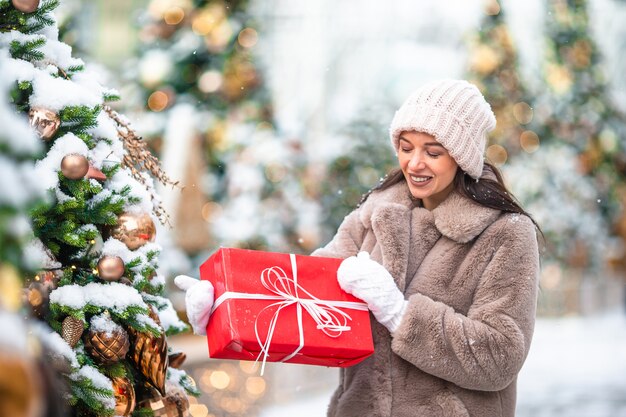 Happy girl near fir-tree branch in snow for new year.