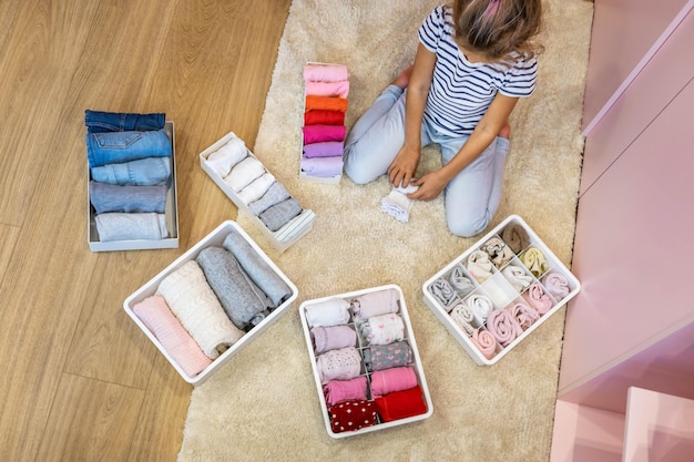 Happy girl neatly roll folded underwear and socks in plastic container box marie kondo method