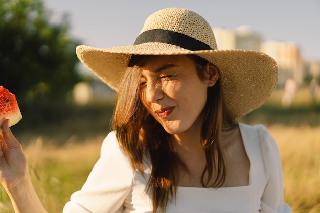 Foto la ragazza felice nel parco all'aperto con la donna rinfrescante della frutta dell'anguria mangia un pezzo di anguria