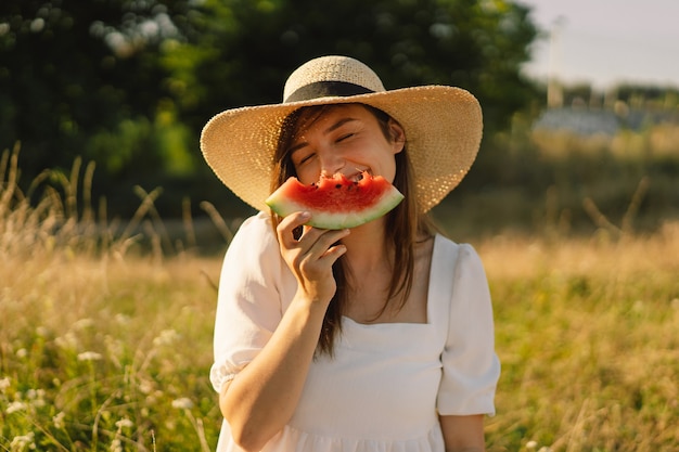 Happy girl in outdoor park with refreshing watermelon fruit woman eats a piece of watermelon