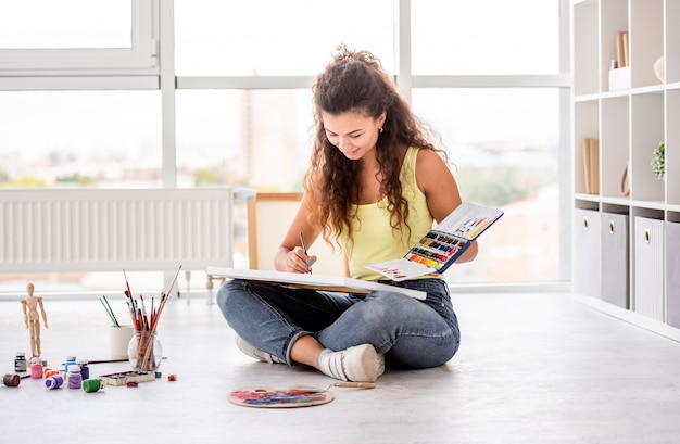 Photo happy girl painting on canvas