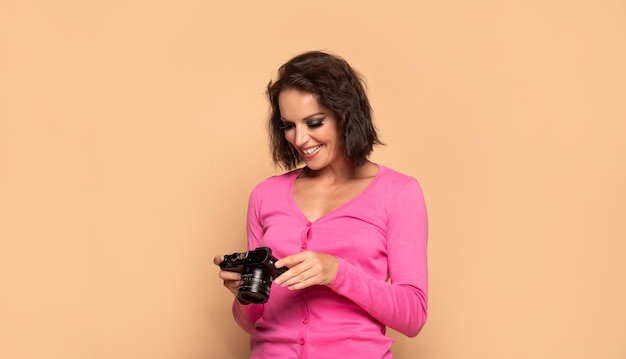 Photo happy girl photographer looking at camera screen beige background photography