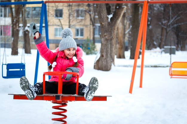 Happy girl playing on a playground at winter frosty day.