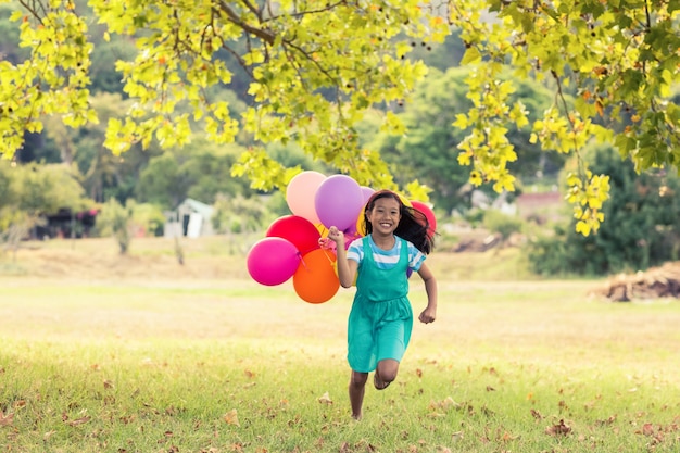 Happy girl playing with balloons in park