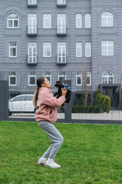 Happy girl playing with dog in her arms on a walk