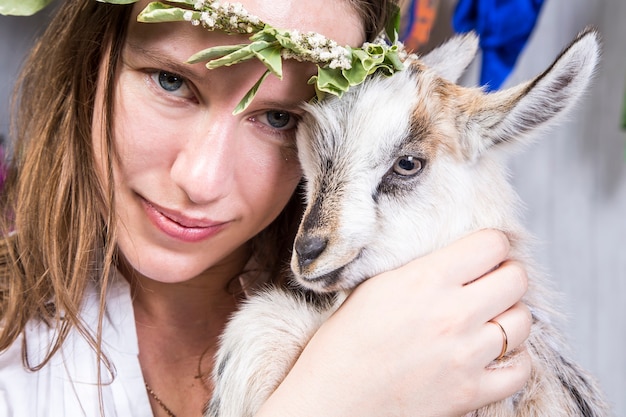 Photo happy girl playing with goats in farmland