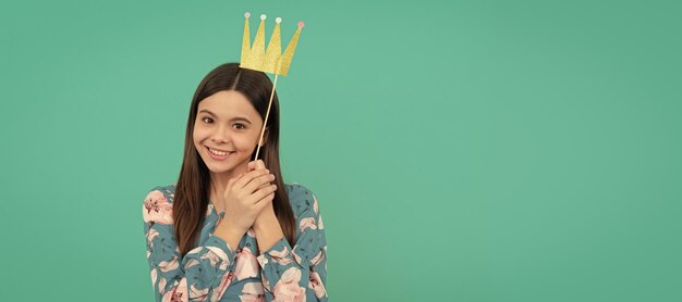 Happy girl princess smile holding prop crown blue background\
prom child queen princess in crown horizontal poster design banner\
header copy space