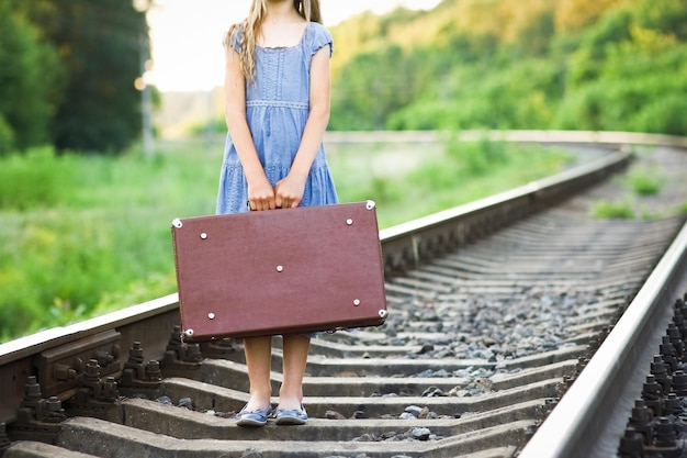 A Happy girl on the railroad with a suitcase tourist journey