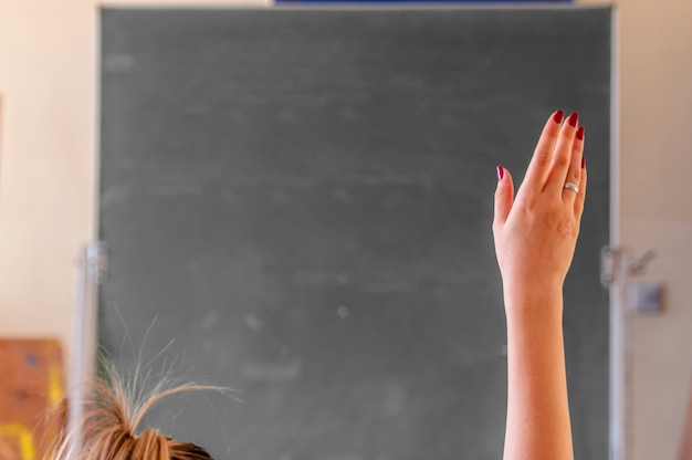 Happy girl raised hands in classroom