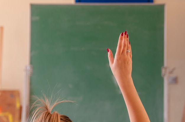 Happy girl raised hands in classroom