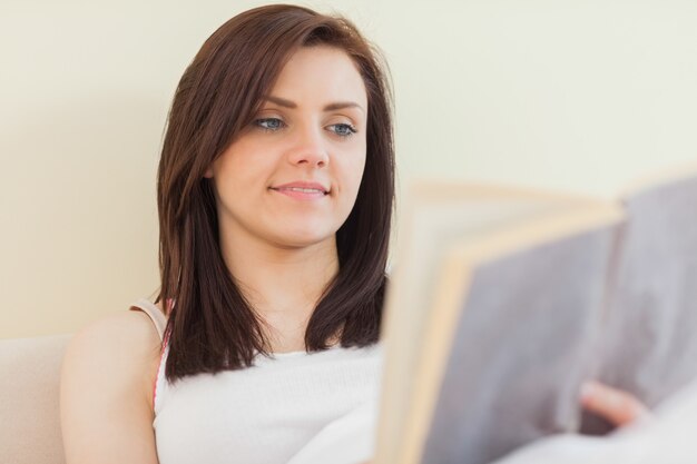 Happy girl reading a book lying on a bed