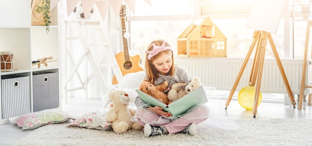 Happy girl reading book with teddies