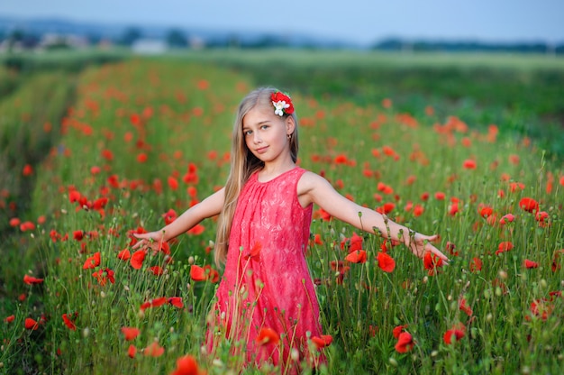 Happy girl in a red dress on poppy field