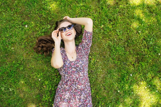 Happy girl relaxing on the lawn lying on back and looking at the sky