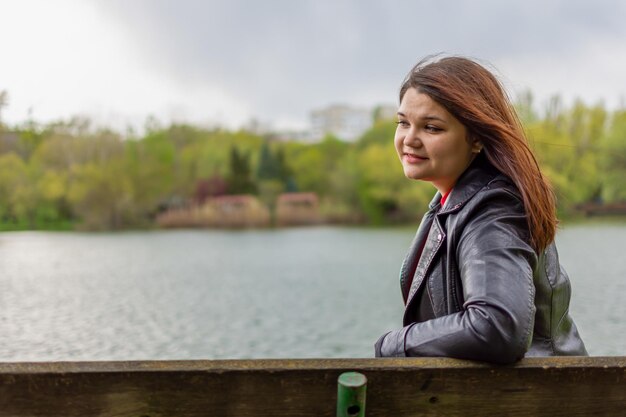 Foto ragazza felice che riposa su una panchina sulla riva del lago