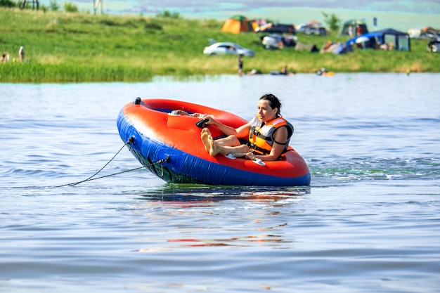 Фото Счастливая девушка катается летом на булочке за лодкой на озере шира