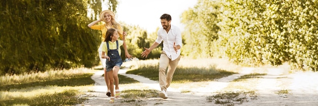 Happy girl running from her parents having picnic in countryside