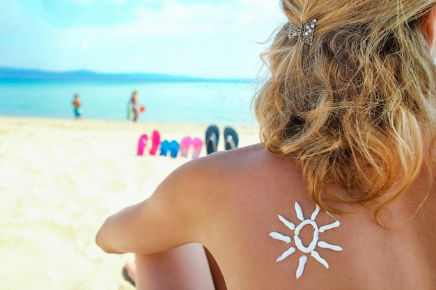 Happy girl on the sea with a picture of the sun on her back