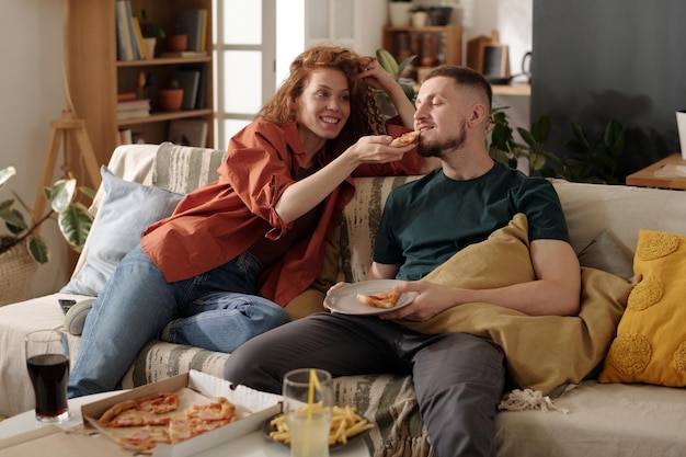 Happy girl sharing pizza with boyfriend