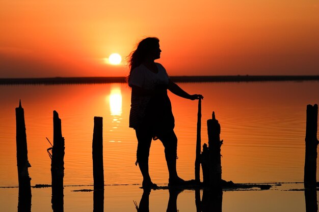 A Happy girl silhouette with reflection bends sea background