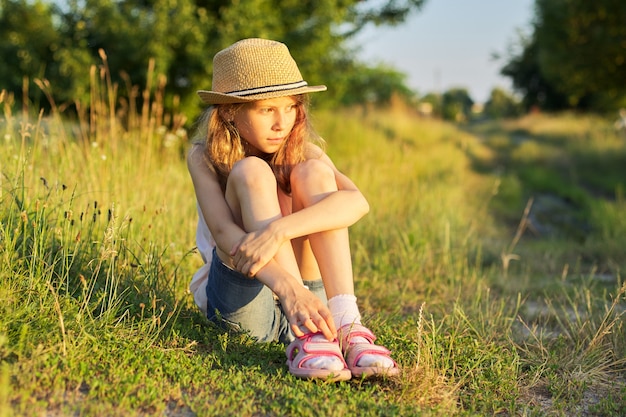 초원에 앉아 여름 휴가를 즐기는 행복한 소녀, 자연 속의 아이, 화창한 날, 일몰 황금 시간