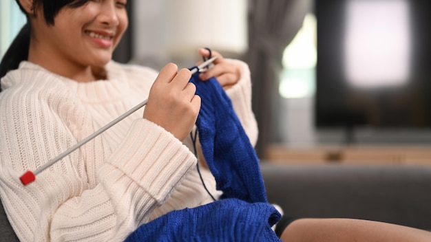 Happy girl sitting on sofa and enjoying knitting