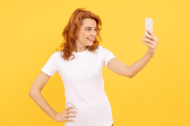 幸せな女の子は携帯電話の黄色の背景のビデオselfieに笑顔