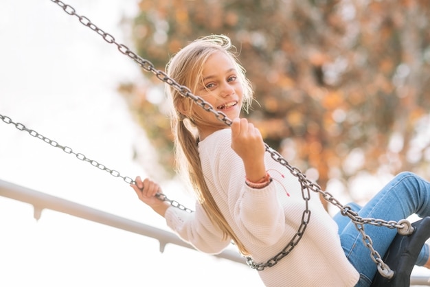 Happy Girl, smiling On Swing In Park at sunset.