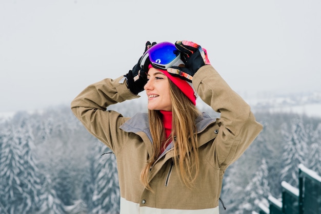 Happy girl snowboarder posing in sunglasses with a snowboard