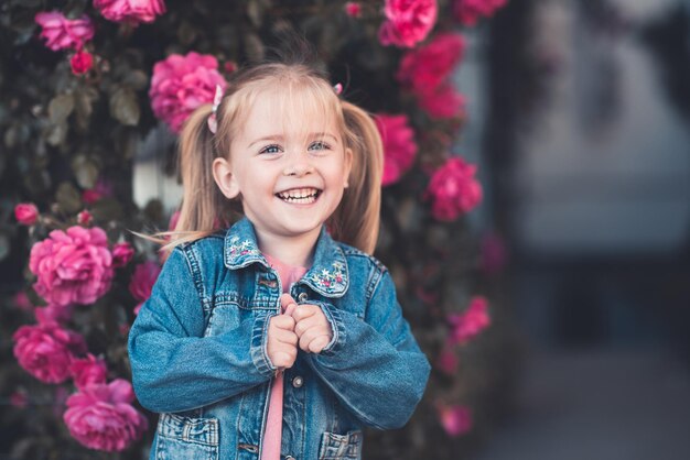 Photo happy girl standing near flowers